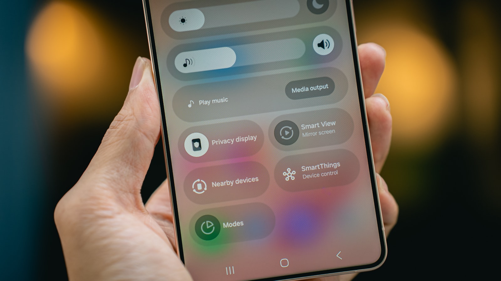 Hand holding a smartphone with privacy and device settings visible on screen.